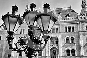 retro style black wrought iron street lamp closeup in black and white. renovated classic old building background