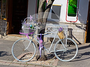 Retro style blue bicycle with lavender flowers as a creative decoration near the shop in the cozy small street