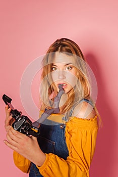 Retro style fashionable woman with film camera on pink background