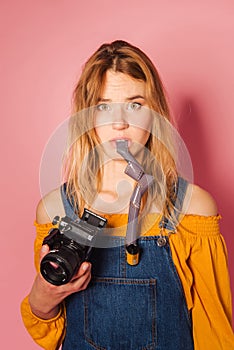 Retro style fashionable woman with film camera on pink background