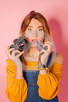 Retro style fashionable woman with film camera on pink background