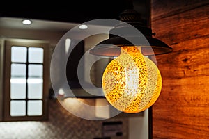 Retro style lamp on the background of the kitchen unit. Round chandelier with warm light in the interior of the living room.