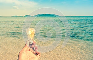 Retro style of man holding lightbulb on the beach with mountain