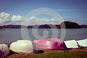 Retro style photo of upturned rowing boats on an empty beach. Bay of Islands, New Zealand. Toned image