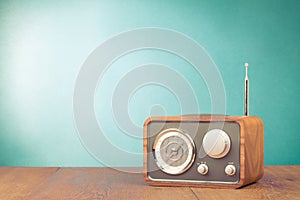 Retro style radio receiver on table in front mint green background