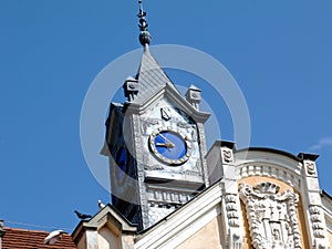 Retro style simple blue tower clock with yellow hands in zink color metal facade