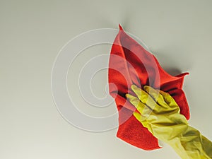 Retro style top view of yellow rubber glove hand and red rug wipe while cleaning a white surface during house domestic chores