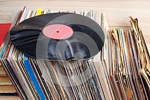 Retro styled image of a collection of old vinyl record lp`s with sleeves on a wooden background. Browsing through vinyl records co