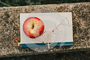 Retro styled image of old book, vintage glasses and red apple