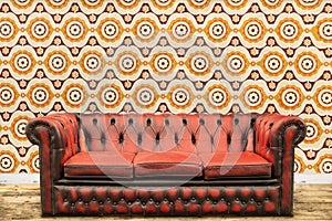 Retro styled image of an old sofa against a vintage wallpaper wa