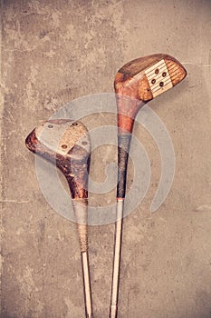 Retro styled image of two weathered ancient golf clubs