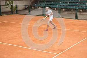 retro styled man in white sportswear playing tennis with racket and ball