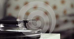 Retro-styled spinning record vinyl player on blur background, closeup side view.