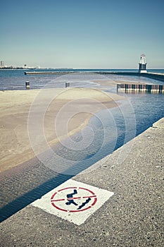 Retro stylized no diving sign on a pier with shallow water in ba