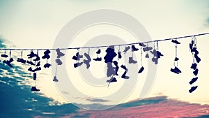 Retro stylized silhouettes of shoes hanging on cable.