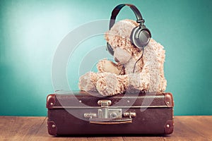 Retro Teddy Bear on old suitcase in front mint blue background. Vintage style photo