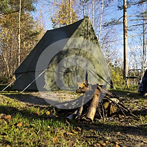 Retro tent in forest and camp fire