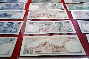 Retro Thai banknotes with different prices placed on red flannel