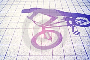 Retro toned blurred shadow of a teenager riding a bmx bike