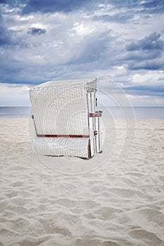 Retro toned hooded wicker chair on beach.