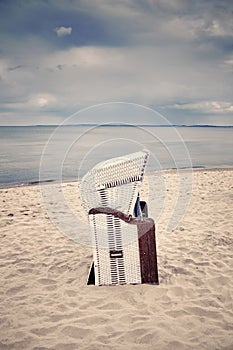 Retro toned hooded wicker chair on empty beach.