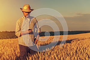 Retro toned image of agronomist farmer using mobile phone