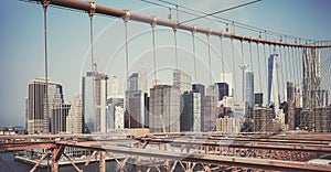 Retro toned picture of New York cityscape seen through Brooklyn Bridge cables, USA