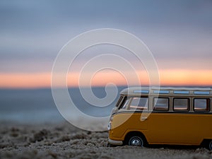 Retro toy car on the beach near the sea against the backdrop of a beautiful sunset.