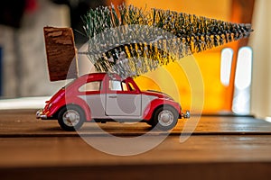 Retro toy car carrying tiny Christmas tree