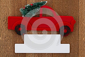 Retro truck with Christmas tree and blank sign on weathered wood