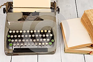 Retro typewriter and old vintage books on white wooden background