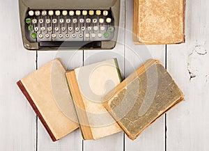 Retro typewriter and old vintage books on white wooden background