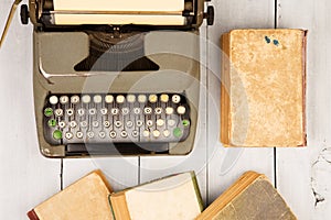 Retro typewriter and old vintage books on white wooden background