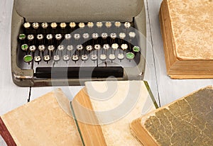 Retro typewriter and old vintage books on white wooden background