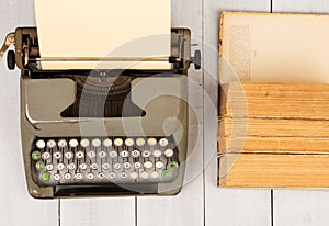 Retro typewriter and old vintage books on white wooden background