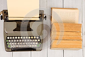 Retro typewriter and old vintage books on white wooden background