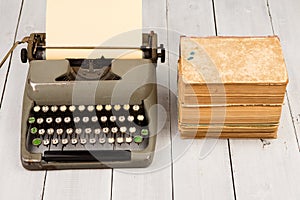 Retro typewriter and old vintage books on white wooden background