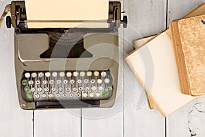 Retro typewriter and old vintage books on white wooden background