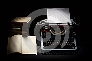 Retro typewriter with stack of book and one opened book photo