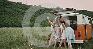 Retro van in the middle of nature, group of beautiful ladies taking selfies, sitting on the back of the van , happy