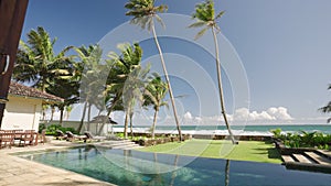 Retro villa living room exit to backyard with swimming pool and ocean shore, horizon, blue sky, palm trees view. Luxury