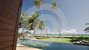 Retro villa living room exit to backyard with swimming pool and ocean shore, horizon, blue sky, palm trees view. Luxury