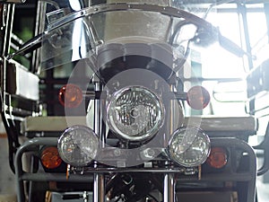 Retro vintage motorcycle front with head and turn signal lamp closeup indoor crop closeup at the headlamp