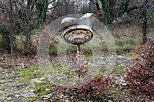 Retro vintage old broken rusted metal street lamp mounted on short metal pole at abandoned public park