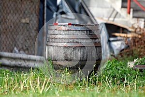 Retro vintage old large wooden wine barrel with rusted metal hoops and dilapidated wooden boards left family house backyard