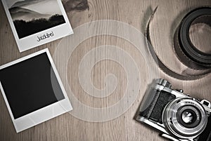 Retro vintage photography concept of two instant photo frames cards on wooden background with old camera and film strip