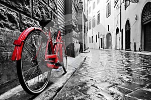 Retro vintage red bike on cobblestone street in the old town. Color in black and white