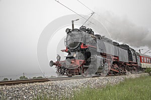 Retro vintage steam locomotive on rail tracks