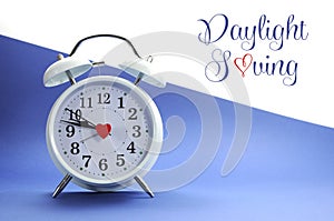 Retro vintage style white alarm clock on blue and white background with Daylight Saving sample text