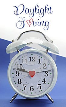 Retro vintage style white alarm clock on blue and white background with Daylight Saving with sample text